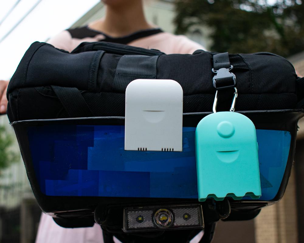 Two AirBeam monitors clipped to a bike handlebar bag on a city ride