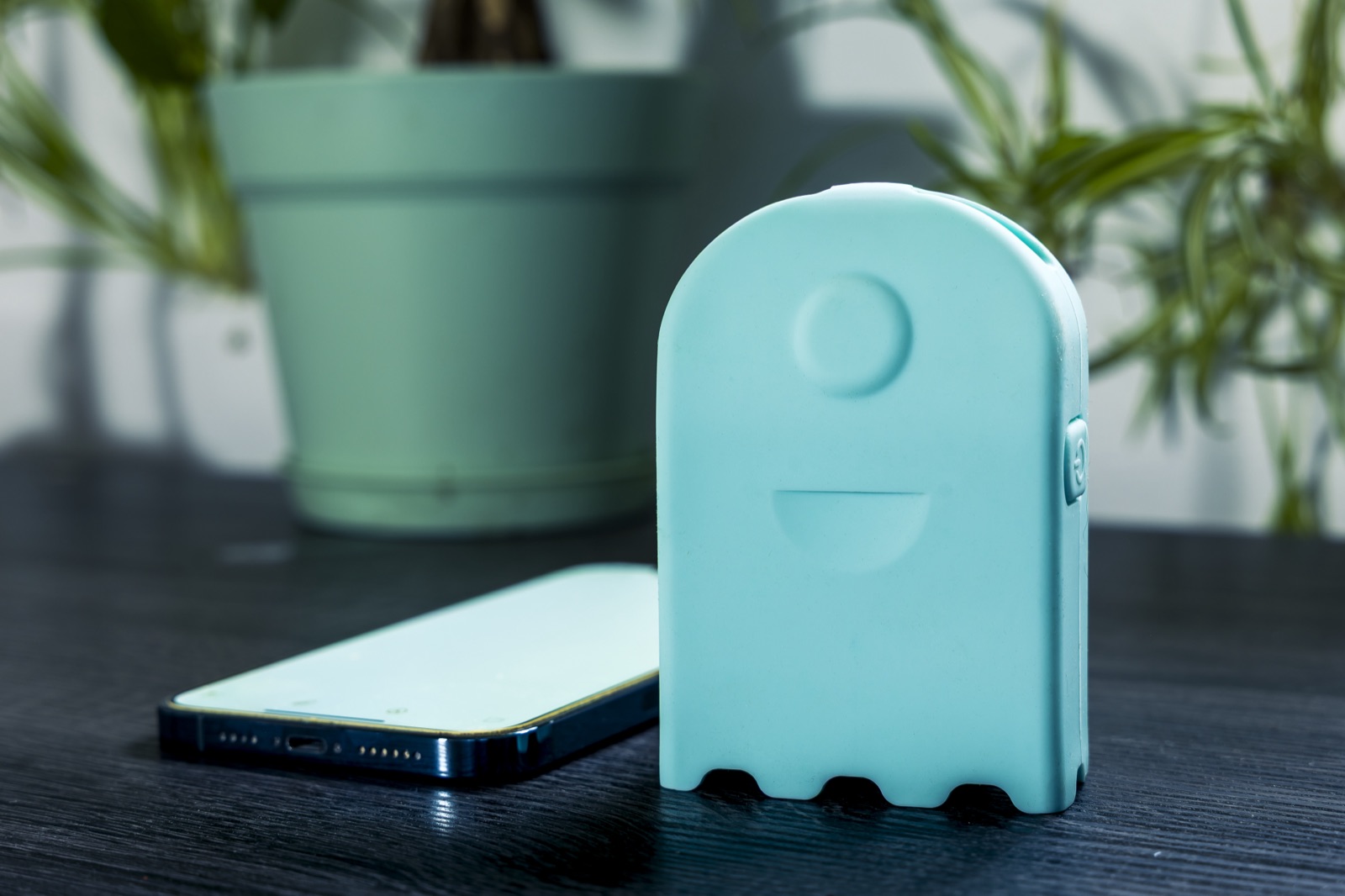AirBeam Mini air quality monitor standing next to a phone